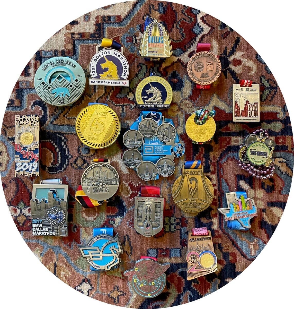 18 marathon medals arranged on a Persian rug — all six World Marathon Majors plus additional races